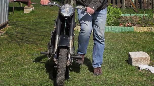 Mies yrittää käynnistää moottoripyörät ulkona
 - Materiaali, video
