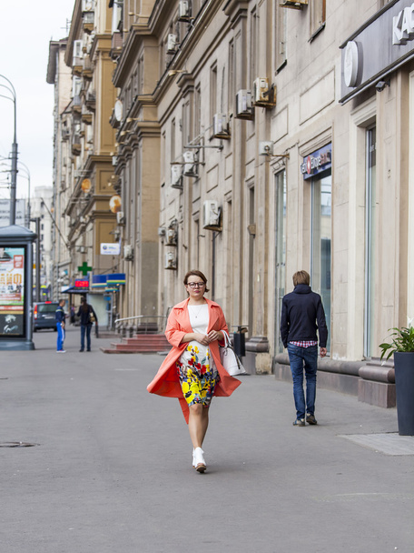 МОСКВА, РОССИЯ, 24 мая 2015 г. Женщина в ярком дождевике идет по улице Сад и Черногорская (Садовое кольцо)
) - Фото, изображение