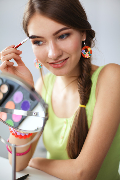Young beautiful woman making make-up near mirror,sitting at the desk - Fotoğraf, Görsel