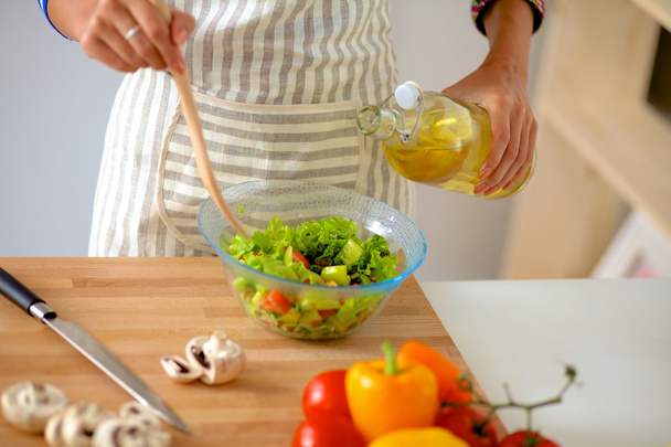 Young woman mixing fresh salad - Foto, afbeelding