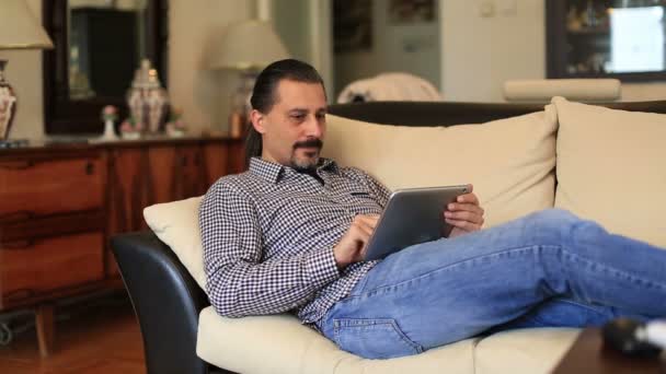 attractive handsome lieying sofa and using tablet computer - Filmagem, Vídeo