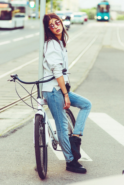 Colorful outdoor portrait of young pretty fashion model with bike. sexy woman posing in summer - Foto, Imagen