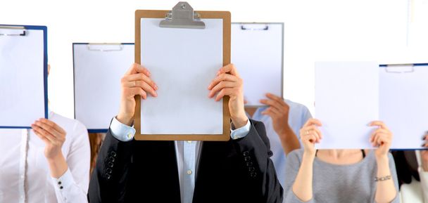 Team of businesspeople holding a folders near face isolated on white background - Fotografie, Obrázek