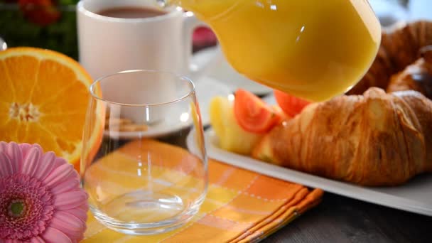 Llenado de vidrio con zumo de naranja en la mesa con desayuno
 - Imágenes, Vídeo