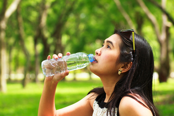 Стокове фото дівчина п'є воду в парку
 - Фото, зображення
