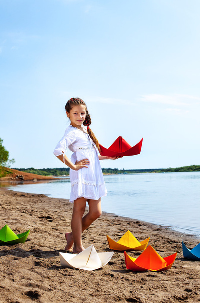 Cute little girl posing with colorful paper boats - Fotoğraf, Görsel
