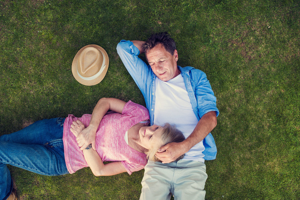 senior couple lying on a grass and hugging - Foto, Imagen