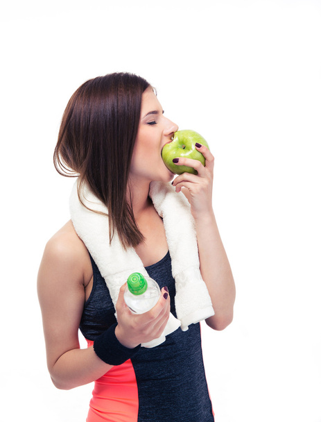 Sporty woman eating apple and holding bottle with water - Foto, afbeelding