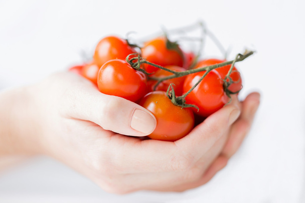 close up of woman hands holding cherry tomatoes - Foto, afbeelding