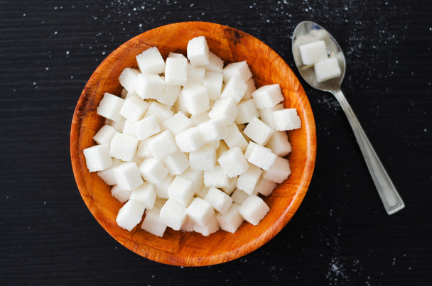 Kostki cukru białego w drewniane miski łyżką na stół ciemny - Zdjęcie, obraz