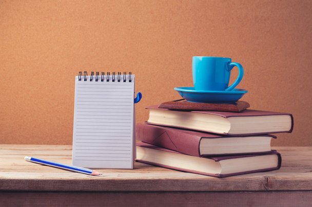 Notizbuch und Kaffeetasse auf Bücherstapel - Foto, Bild