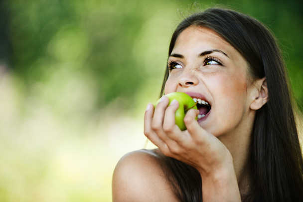 Портрет молодой очаровательной женщины, кусающей яблоко
 - Фото, изображение