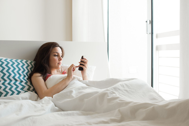 Mujer en la cama con smartphone - Foto, imagen