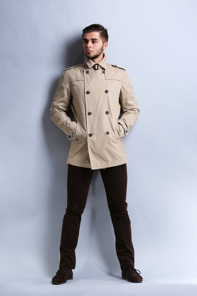 Young man in coat on gray background - Foto, Imagem