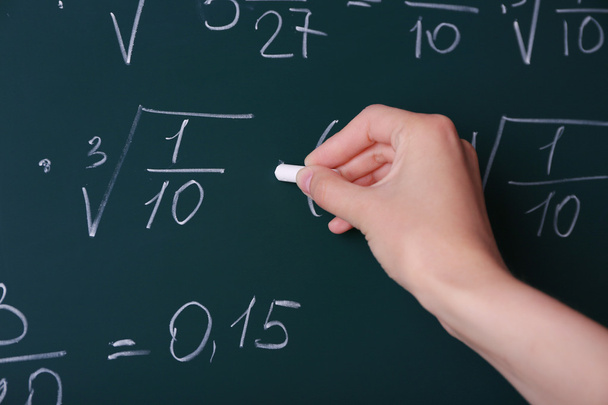 Female hand writing formulas on blackboard - Фото, изображение
