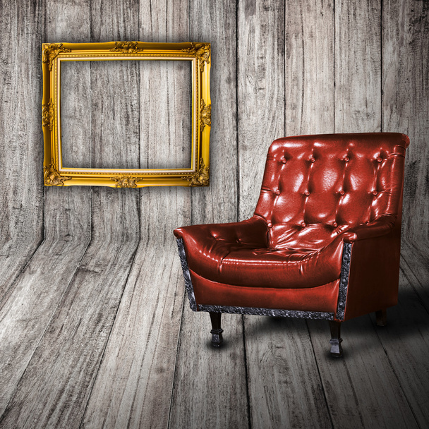 Sofá de couro na sala de madeira com moldura vintage dourada na parede
 - Foto, Imagem