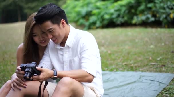 Aziatische paar buiten picknick kijken naar hun eigen selfies - Video
