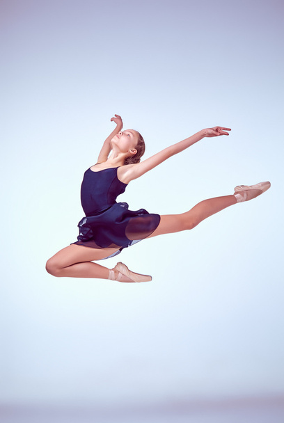 Όμορφη νεαρός μπαλέτου χορευτής άλμα σε ένα γκρίζο φόντο.  - Φωτογραφία, εικόνα