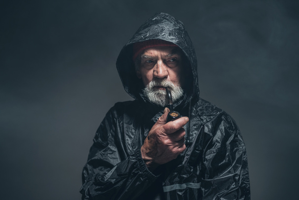 Reflecterende oude man in de jas - Foto, afbeelding