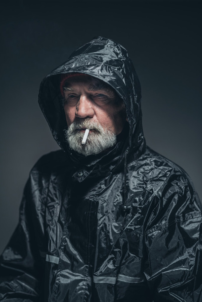 Pohdiskeleva vanha mies musta sadetakki
 - Valokuva, kuva