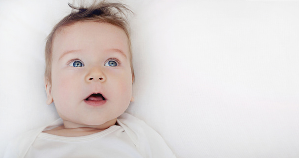 portrait of cute little baby boy lying on soft white pillow - 写真・画像