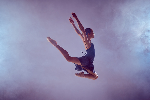 Beautiful young ballet dancer jumping on a lilac background.  - Foto, afbeelding