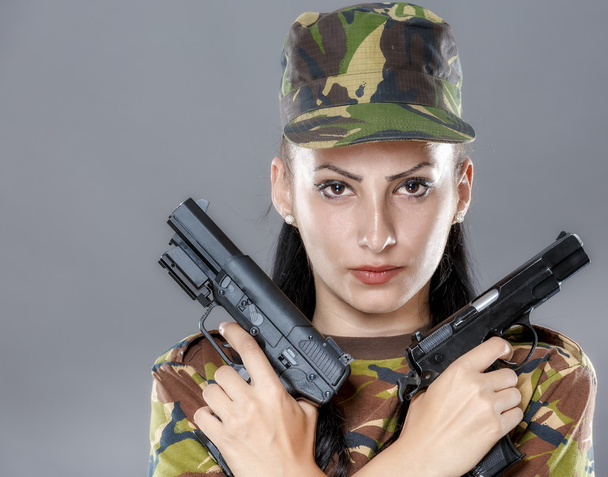 Soldato donna in uniforme mimetica con arma isolata su sfondo grigio
 - Foto, immagini