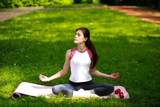 Sportive young woman relaxing in sunshine, doing yoga exercises - Foto, Imagem