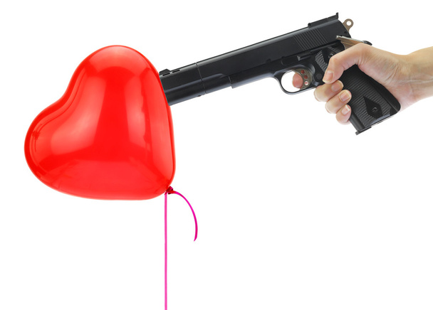 Hand holding at gunpoint a heart balloon isolated on white - Photo, Image