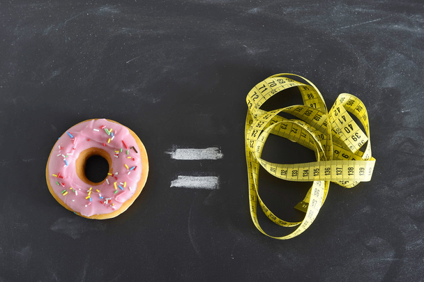donut and tailor measure tape on blackboard in sugar sweet abuse and addiction equal body overweight - Photo, Image