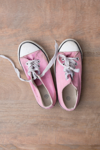 Close up of pink sneakers worn by a teenager on wooden background - Photo, Image