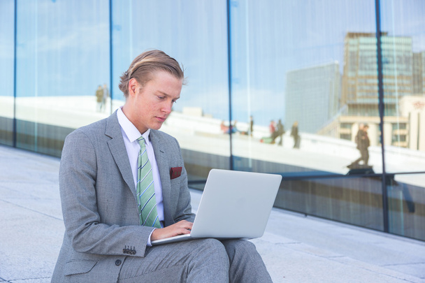 Jeune homme à la mode travaillant avec ordinateur portable en plein air
 - Photo, image