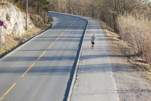 man running outside along an empty road - Photo, Image