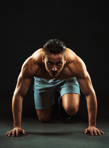 Sport attractive man doing fitness exercises on the black - Foto, afbeelding