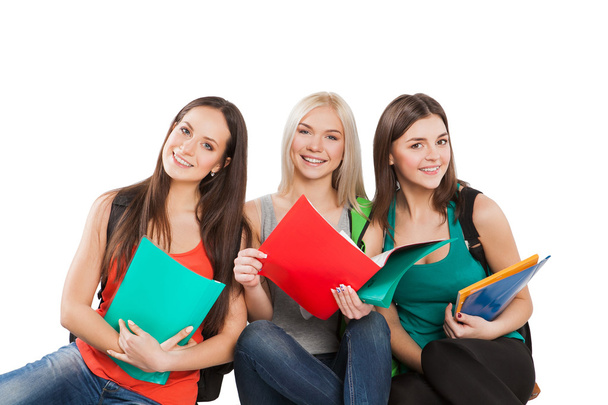 three students girl with copybooks sitting together on a white background - Photo, Image