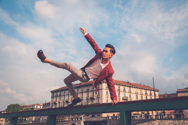 Handsome Asian model jumping in the city streets - 写真・画像