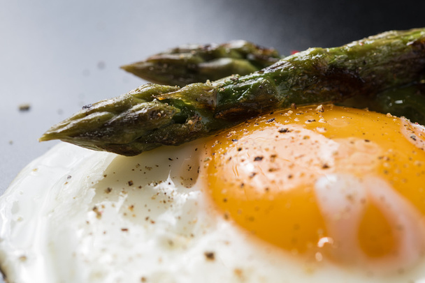 Fried egg and roasted asparagus in black plate - Photo, Image