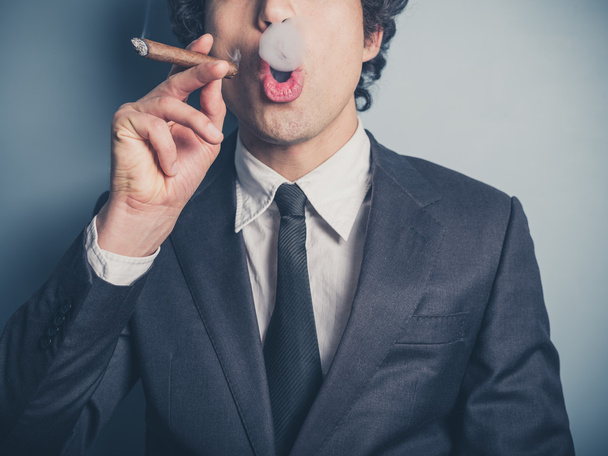 Young businessman blowing smoke rings - 写真・画像