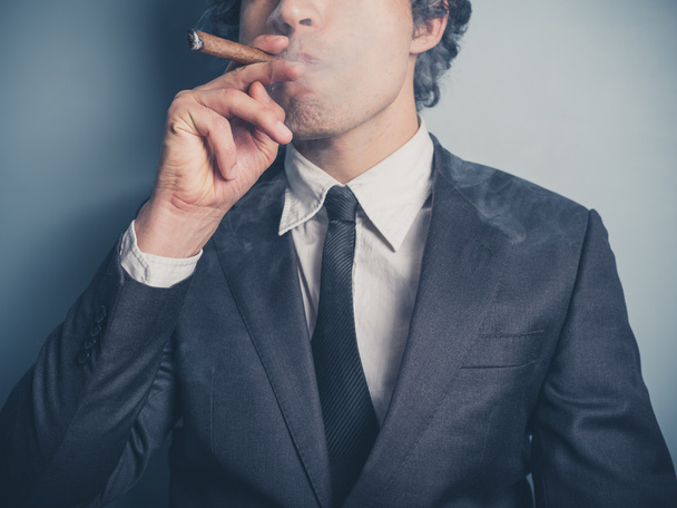 Young businessman smoking a cigar - Фото, изображение