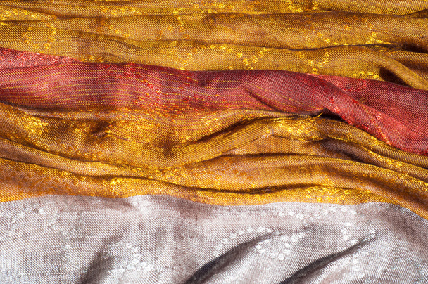 De textuur van wol stof geel rood gouden. Vrouwen sjaal, de perfecte achtergrond. Cravat scoutingdas, bandana, uitlaat, gooien. een lengte of vierkant van weefsel rond de nek of hoofd gedragen. - Foto, afbeelding