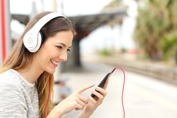 Teen girl listening to the music with headphones waiting a train - Fotoğraf, Görsel