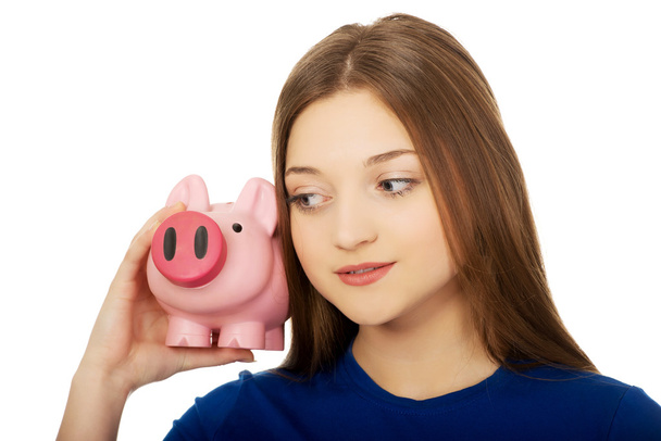 Teenage woman holding piggybank. - Foto, Bild
