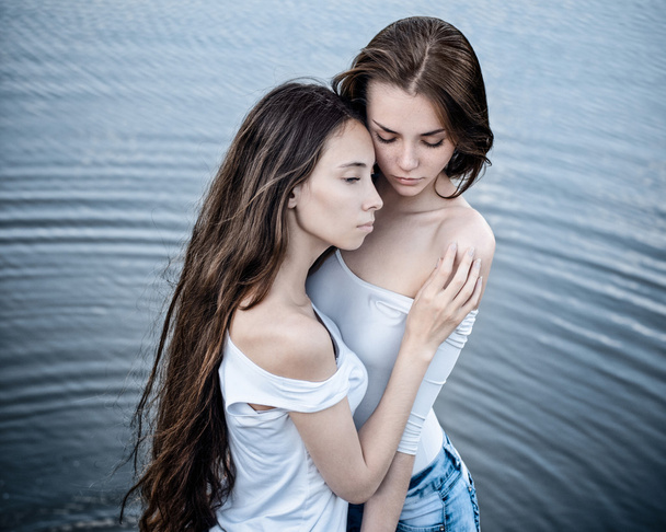 Dramatic portrait of a girl portrait of two beautiful girls on a background of water - Zdjęcie, obraz
