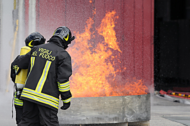 酸素ボンベで消防士が訓練中に火を消してください。  - 写真・画像
