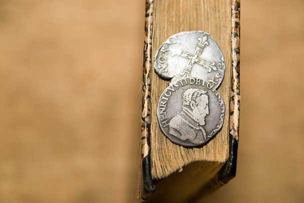 French old coin with a portrait of the King is on the book - Photo, Image