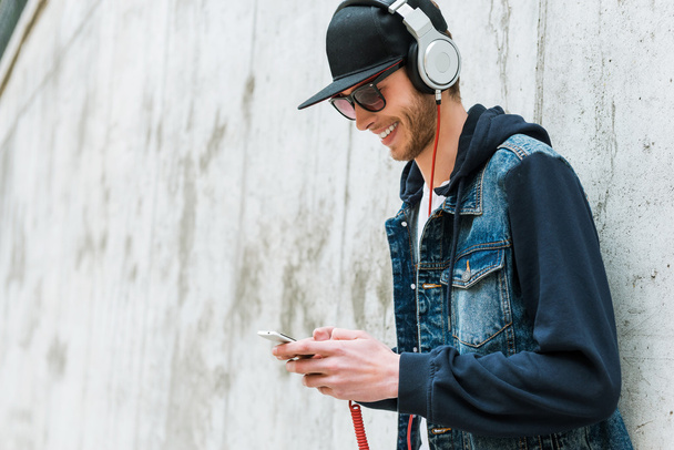 Mann mit Kopfhörer hält Handy in der Hand - Foto, Bild