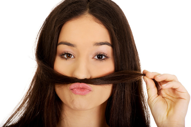 Teen woman putting hair like moustache. - 写真・画像
