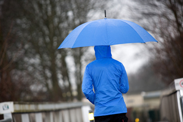 Regen lopen met zijn paraplu en regenjas - Foto, afbeelding