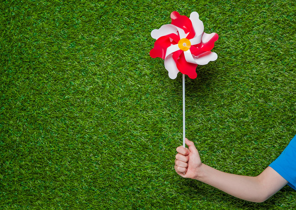 Human hand holding pinwheel over grass - Foto, afbeelding