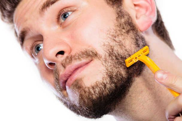 Young man with beard holding razor blade - Фото, изображение